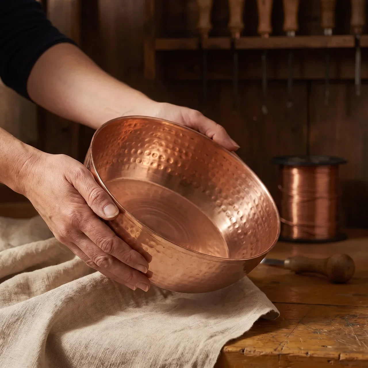 Copper serving bowl with hammered texture, held by two hands.