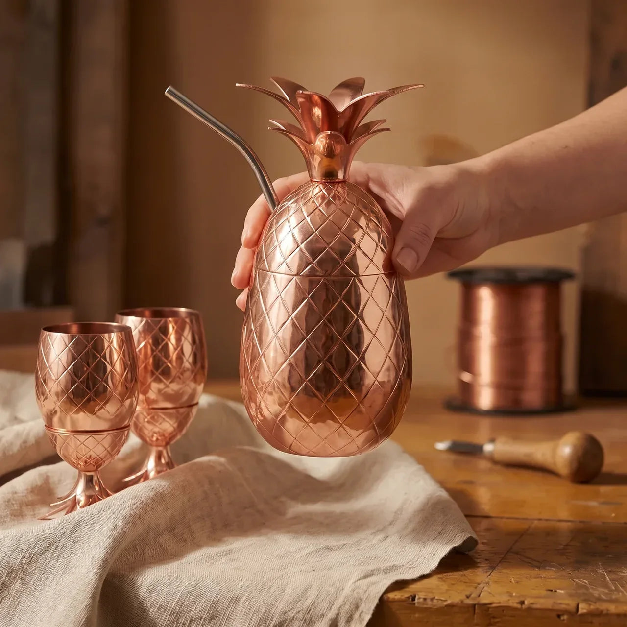 Copper pineapple-shaped pitcher and two goblet-style cups with engraved lattice texture