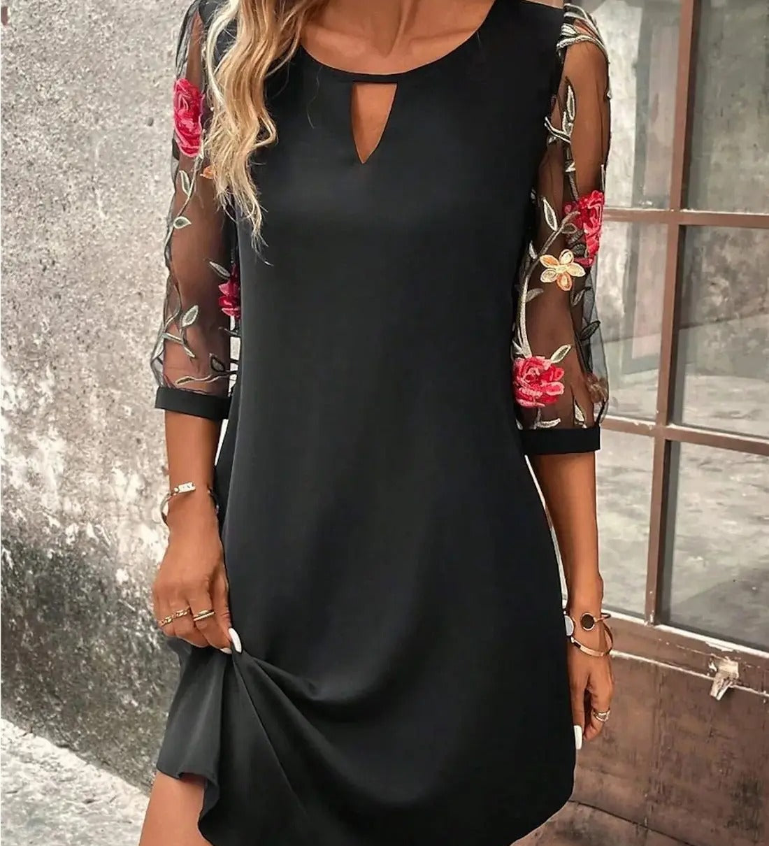 Black shift dress with cutout neckline, sheer floral sleeves, and draped hem