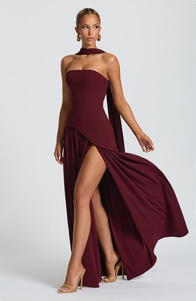 Burgundy strapless maxi dress with high leg slit and flowing cape-like back overlay