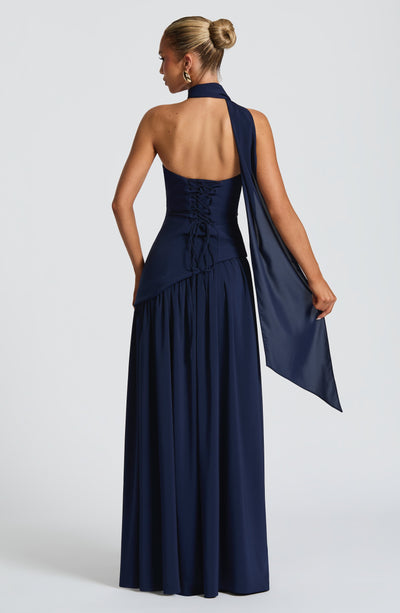 Women’s strapless navy maxi dress with open back and flowing skirt, draped side panel.
