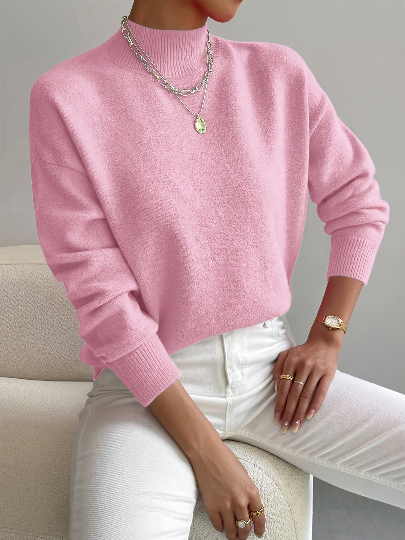 Women’s light pink knit pullover with rolled neckline and long sleeves, relaxed fit.