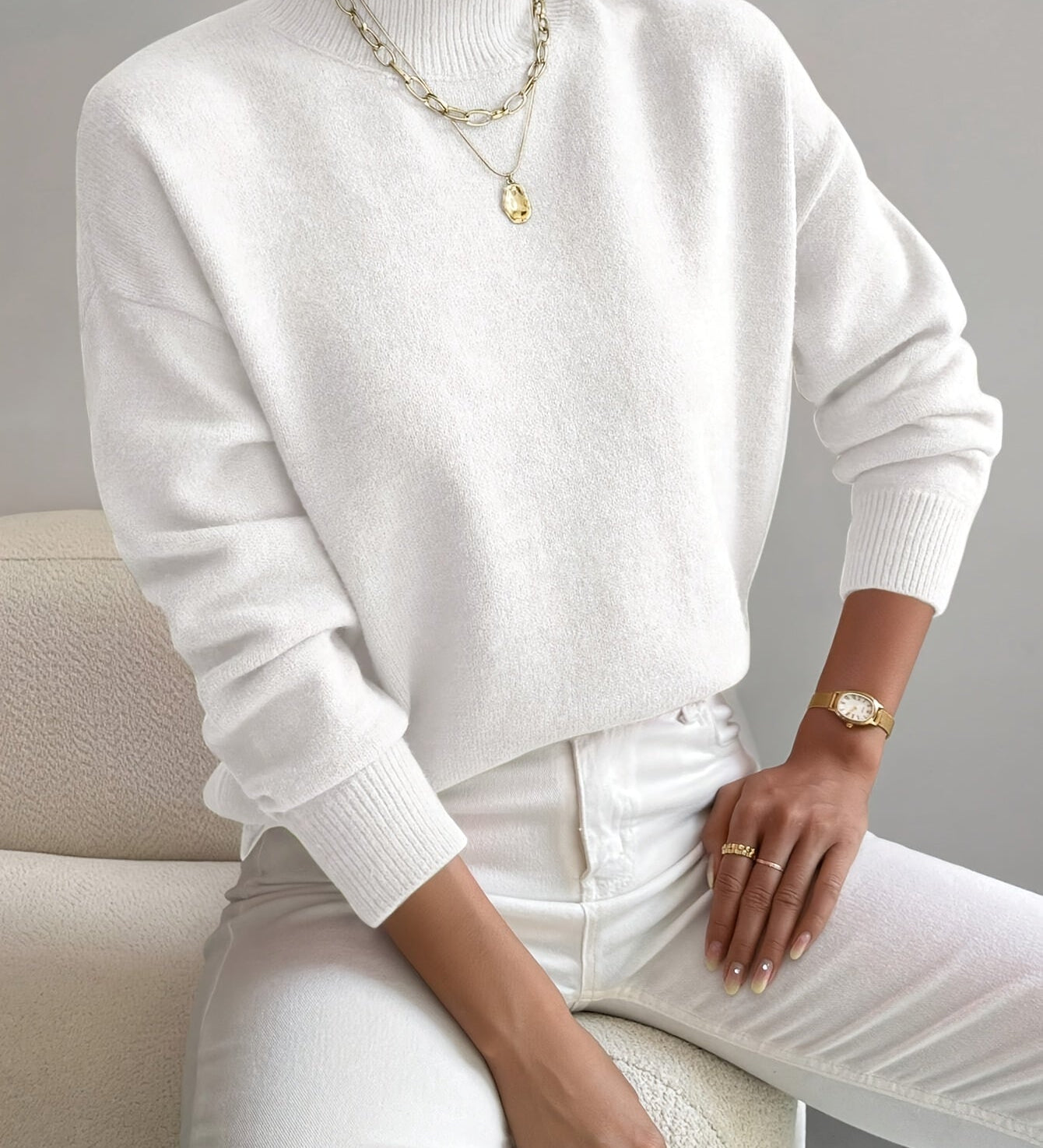 Women’s white knit pullover with rolled neckline and long sleeves, relaxed fit.