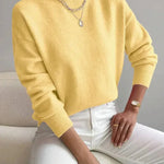 Women’s yellow knit pullover with rolled neckline and long sleeves, relaxed fit.
