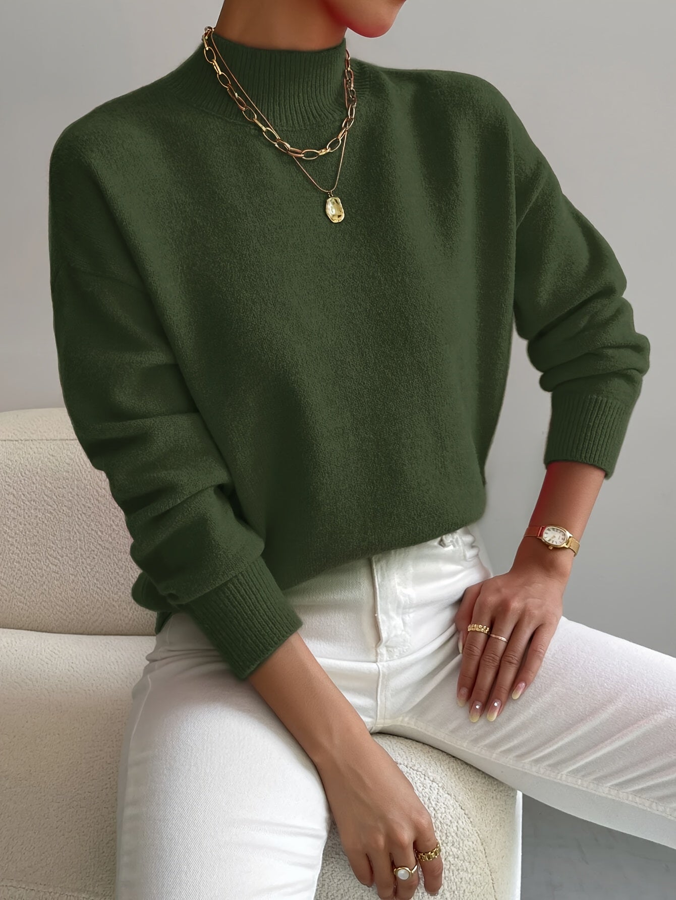 Women’s dark green knit pullover with rolled neckline and long sleeves, relaxed fit.