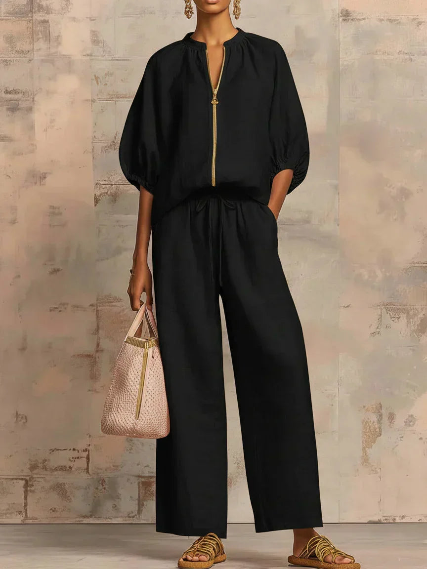 Black two-piece blouse and wide-leg pants set with gold front zipper and drawstring waist