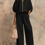 Black two-piece blouse and wide-leg pants set with gold front zipper and drawstring waist