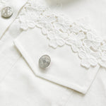 White jacket close-up with silver buttons and embroidered lace yoke