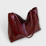 Dark red slouchy tote bag with double handles and smooth glossy finish