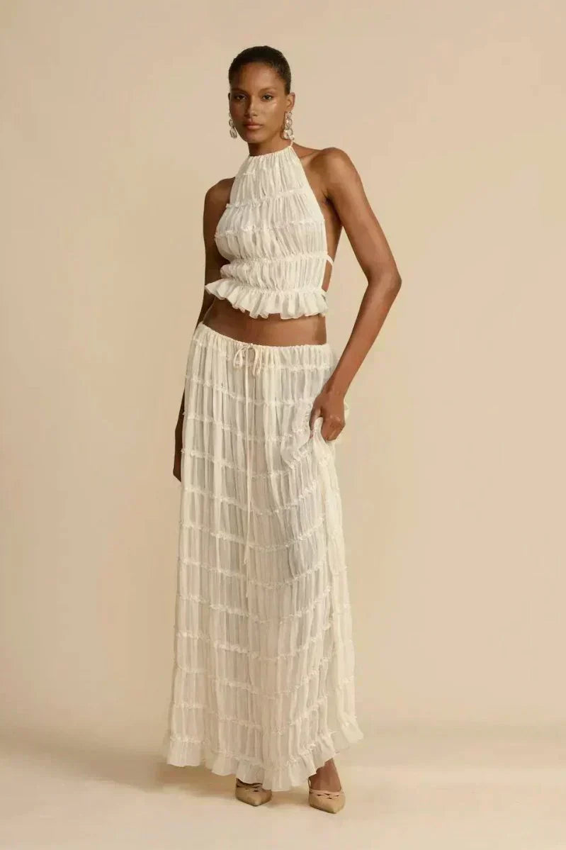 White pleated halter crop top with ruffled tiers, styled with a long tiered skirt