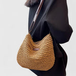 Tan woven crescent shoulder bag with long brown strap and front patch