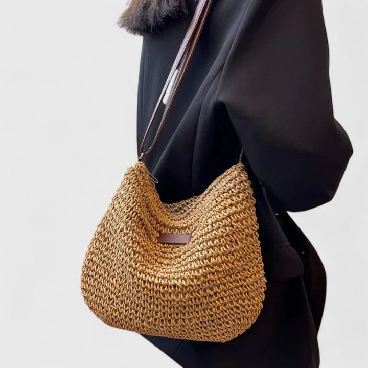 Tan woven crescent shoulder bag with long brown strap and front patch