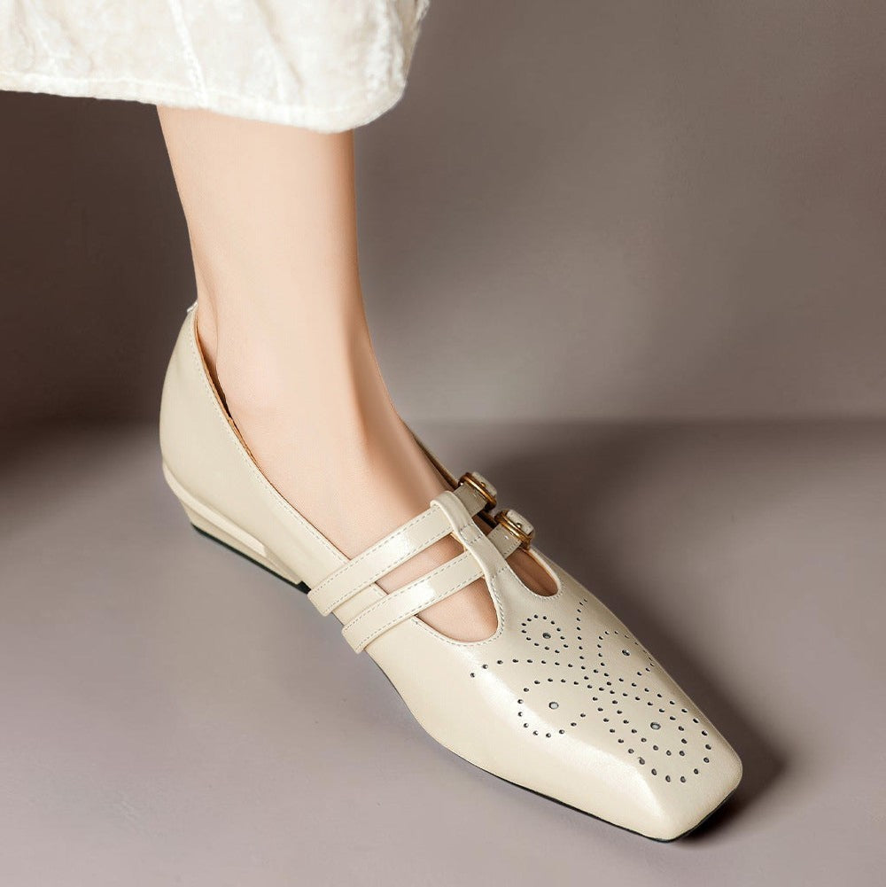 Cream Mary Jane flats with double straps, brogue perforations, gold buckles