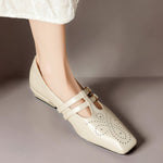 Cream Mary Jane flats with double straps, brogue perforations, gold buckles