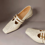 Cream Mary Jane flats with strap across vamp, brogue perforations, gold buckle