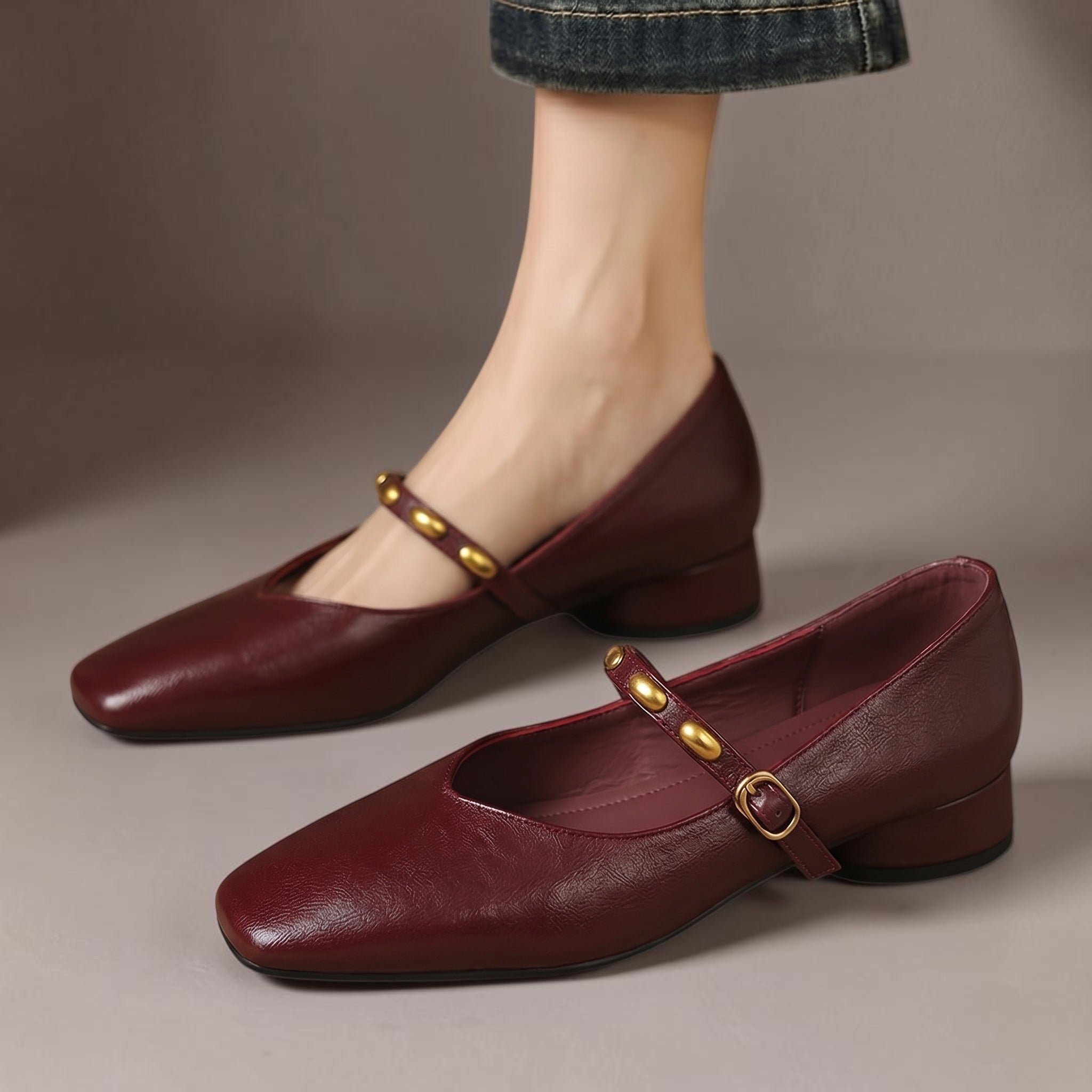 Burgundy leather ballet flats with rounded toe, low block heel, and gold buckle strap