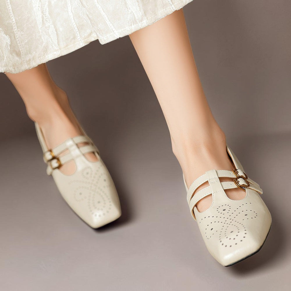 Cream Mary Jane flats with strap details and brogue perforations, gold buckle