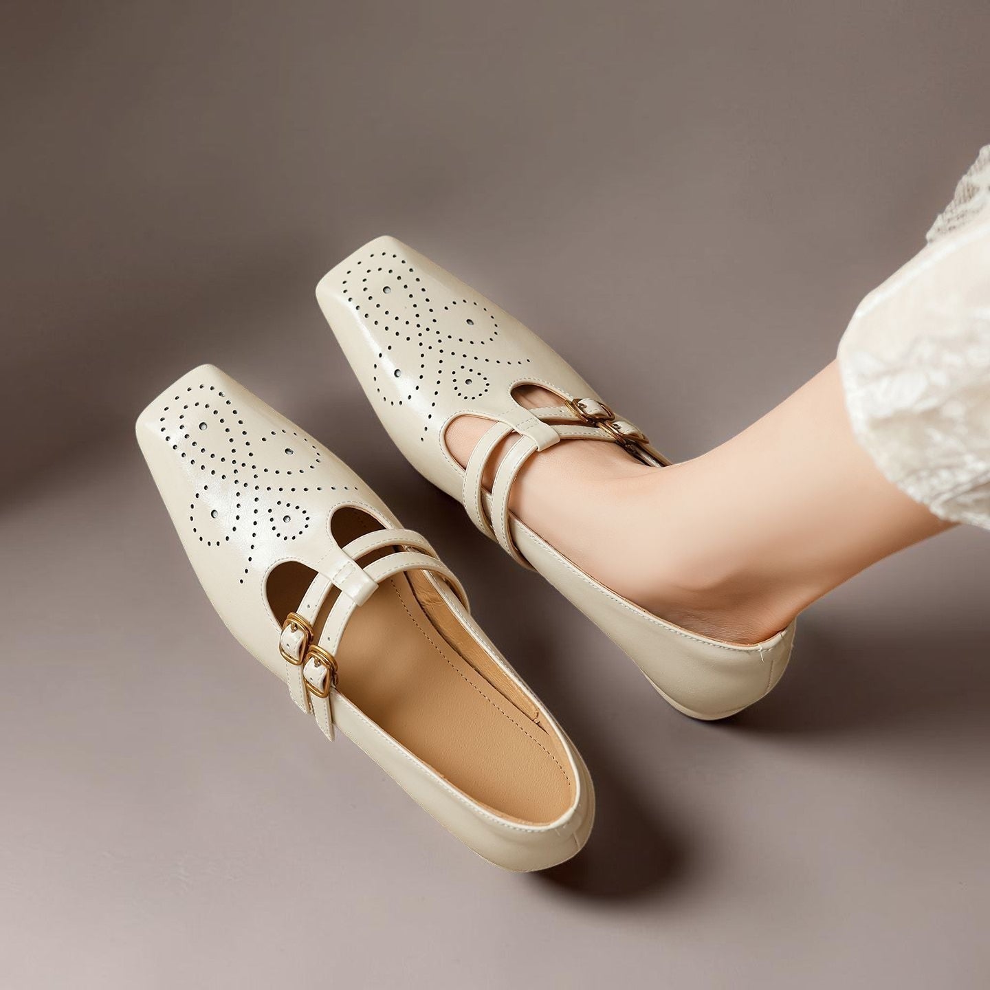Cream Mary Jane loafers with two buckle straps and brogued perforation design