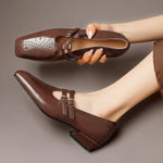 Brown Mary Jane loafers with double straps, buckle closure, and broguing perforations