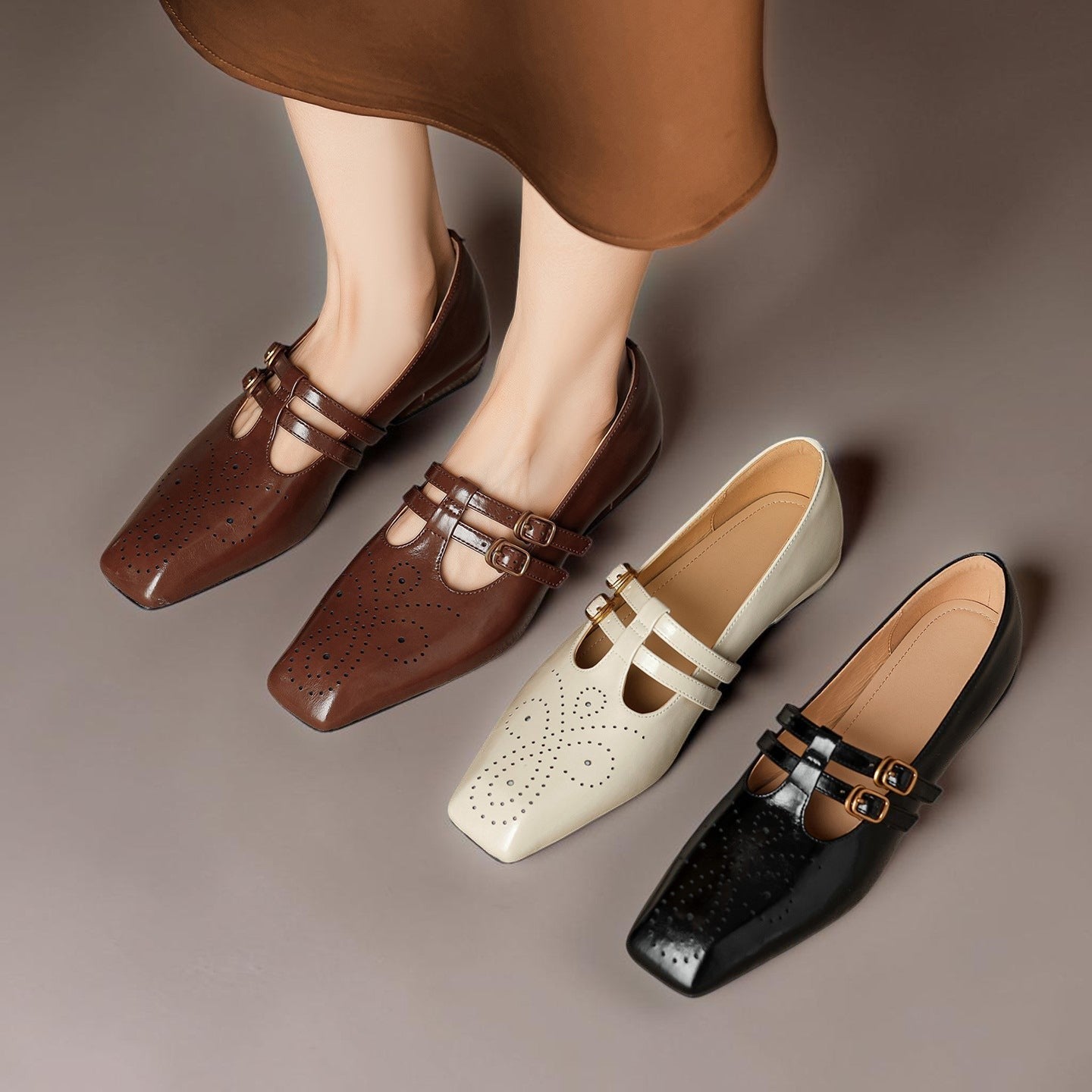 Brown, cream, and black Mary Jane flats with buckle straps and brogue perforations