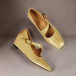 Pair of yellow leather Mary Jane heels with adjustable buckle strap, angled view